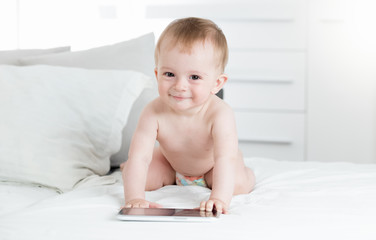 Fototapeta premium Adorable baby boy using digital tablet on bed