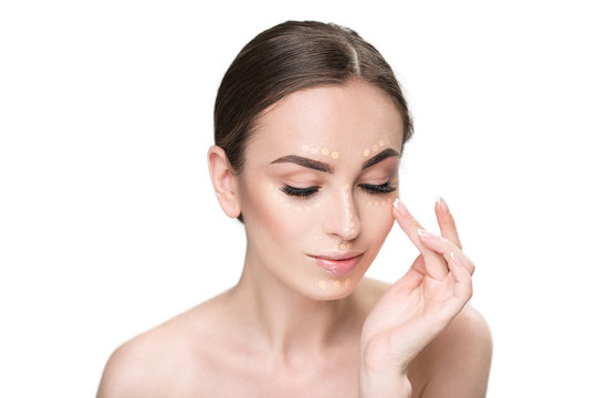 Assured young lady using concealer