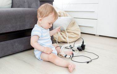 Baby boy pulling cables from electrical extension