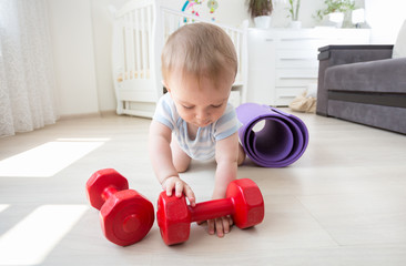 Baby boy playing with dumbbells on floor at home