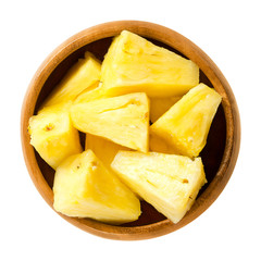 Pineapple pieces in wooden bowl. Ananas comosus, the edible multiple fruit of a tropical plant, consisting of coalesced berries. Yellow flesh. Macro food photo close up from above on white background.
