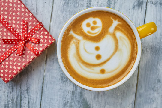 Coffee And Present, Top View. Latte With Snowman Art. Non Alcoholic Christmas Drink Ideas.
