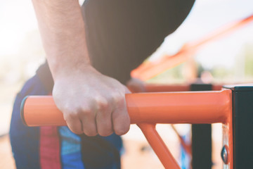 A portrait of a focused muscular bearded man in black workout clothes doing dips on parallel bars . Mans fitness with blue sky in the background and open space around him. Sports and crossfit