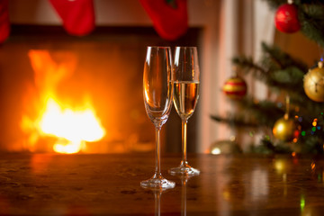 Glass with champagne on table in front of burning fireplace