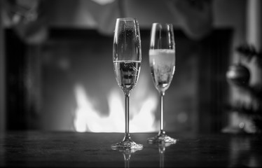 Black and white image of bottle filling glasses with champagne on Christmas table