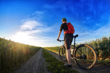 Rear view of the cyclist riding mountain bike on the trail against beautiful sky.