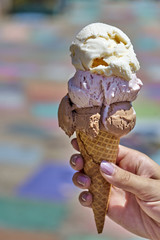 Summertime enjoyment: Female hand holding three scoop ice cream waffle cone 