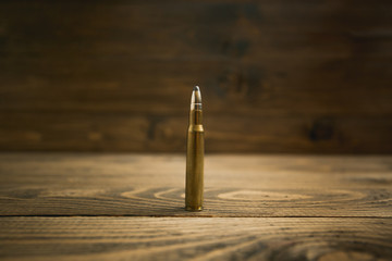 Closeup image of riffle bullet on old wooden desk