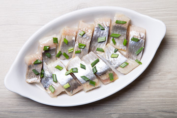 Pieces of herring with onions on a white plate. Selective focus