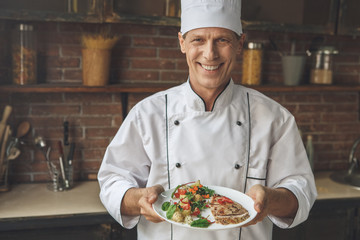  Mature man professional chef cooking meal indoors