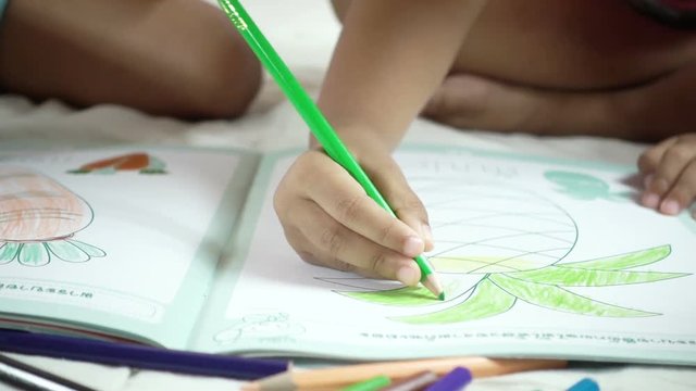 Slow motion of child hand holding the crayon and painting her picture