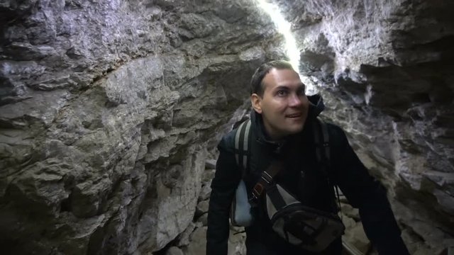 Male Traveler Walking Through Tight Tunnel Inside Cave