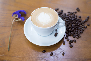 Coffee cup and coffee beans on table on a wooden desk