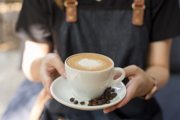 Barista is holding  latte art in hand