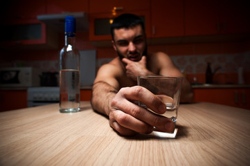 Young caucasian man drinking alcohol at home