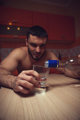 Young man drinking alcohol in kitchen at home.