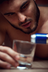Young caucasian man drinking alcohol at home