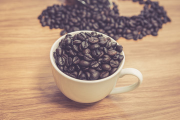 Coffee beans and cup on wooden background, warm tone