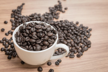 Coffee beans and cup on wooden background, warm tone