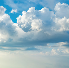 Blue sky with white clouds at sunny day. Abstract natural background with thick fluffy clouds