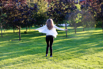 A young girl is spinning in the park for joy