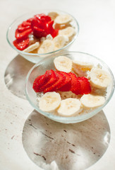 Two bowls of curd with strawberry and banana.