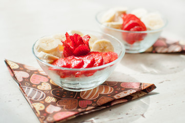 Two bowls of curd with strawberry and banana.