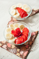 Two bowls of curd with strawberry and banana.