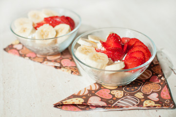 Two bowls of curd with strawberry and banana.