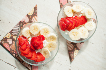 Two bowls of curd with strawberry and banana.