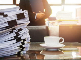 Close up of stack of documents and a cup of coffee on businessman working background