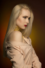Gorgeous young model with bright makeup in red color and gold foil on her neck