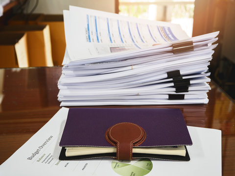 Close up of notebook and business documents stack on desk