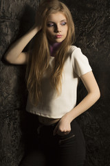 Wonderful young woman with long blonde hair posing in dark room