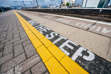 Fototapeta premium Mind the step yellow text line in British train station - visiting United kingdom taking care and security measures while traveling with train 