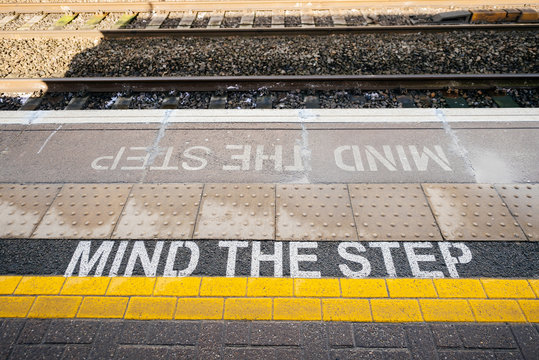 Directly above view of Mind the step yellow text line in British train station - visiting United kingdom taking care and security measures while traveling with train 
