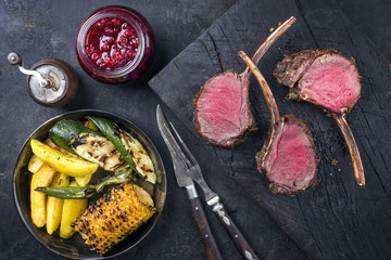 Barbecue Rack of Venison with Potatoes and Vegetable as top view on an old burnt wooden board