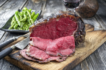 Barbecue dry aged Rib of Beef with green Asparagus as close-up on an old cutting board
