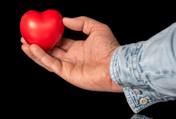 Fototapeta premium Hand holds a red heart on display