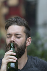 Cute bearded guy drinking beer from bottle. Outdoors