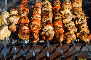 Grilled kebab cooking on metal skewer closeup. Roasted meat cooked at barbecue. Traditional eastern dish, shish kebab. Grill on charcoal and flame, picnic