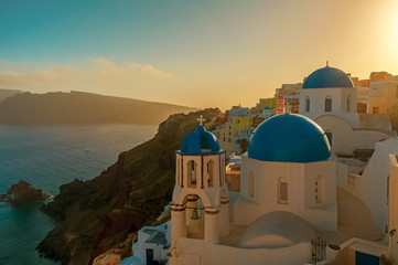 Typical postcard shot of Greek houses and blue dome churches by sunset in the island of Santorini