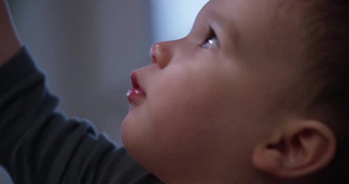 close up on toddler boy curious face - reaching up