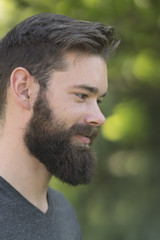 Close up profile portrait of a fascinating bearded guy in park