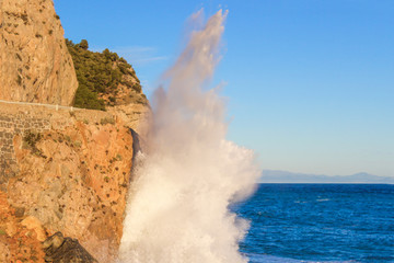 Soft focus. Beautiful sea waves crashing against the cliffs with white foam on a blue ocean surface.