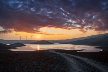 Fototapeta na wymiar sunset over lake with wind generator in horizon 