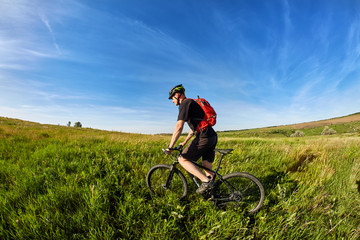Naklejka premium Young cyclist riding mountain bicyclist against beautiful sunrise in the countryside.