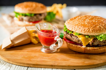 American classic hamburger with beef, tomato sauce and french fries on wood table. Top view. Tasty food