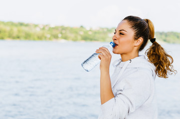 Beautiful fitness athlete woman drinking water after work out exercising