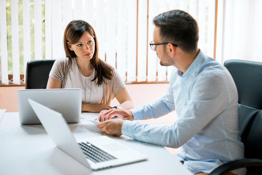 Image of two young business partners talking in office